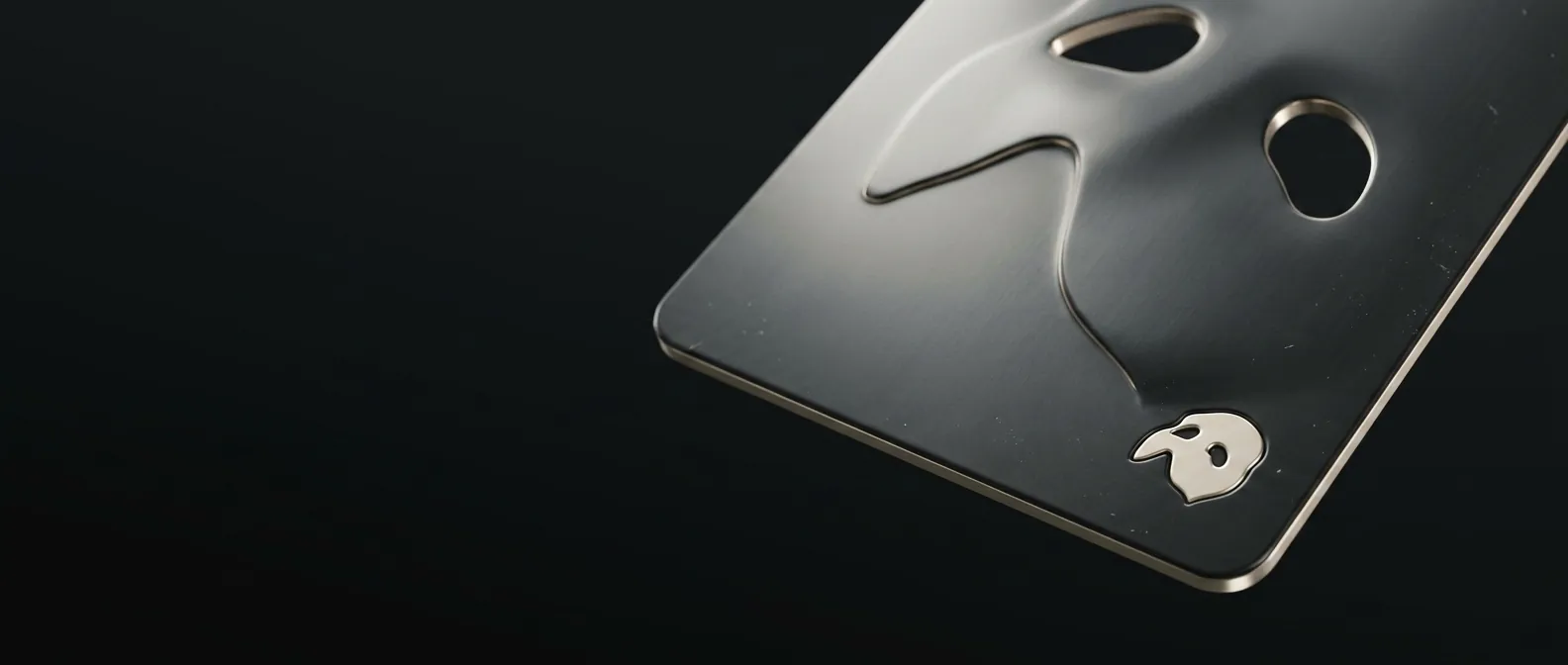 A blank metal sheet carrying a single small embossed Phantom mask seal in its corner.